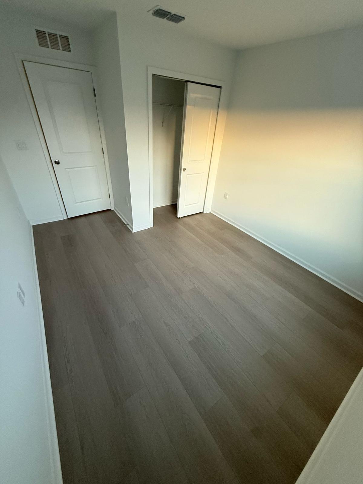 Mid-grey wood-look laminate flooring installed in a residential bedroom