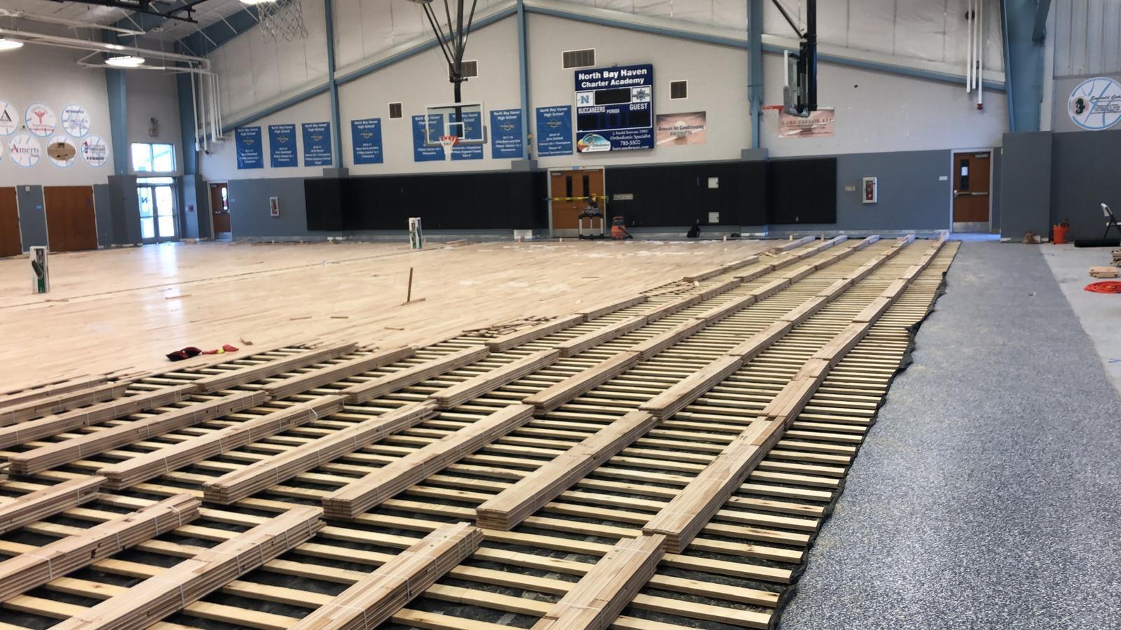 Maple gymnasium hardwood strips bundled mid-install at North Bay Haven Charter Academy