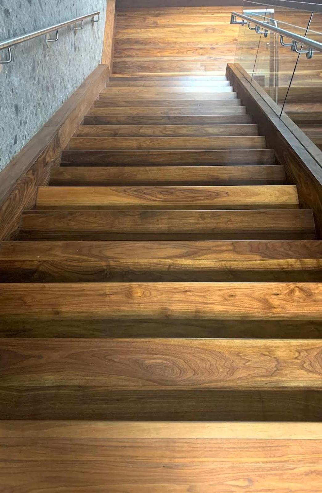 Walnut-tone hardwood stair treads with modern glass railing