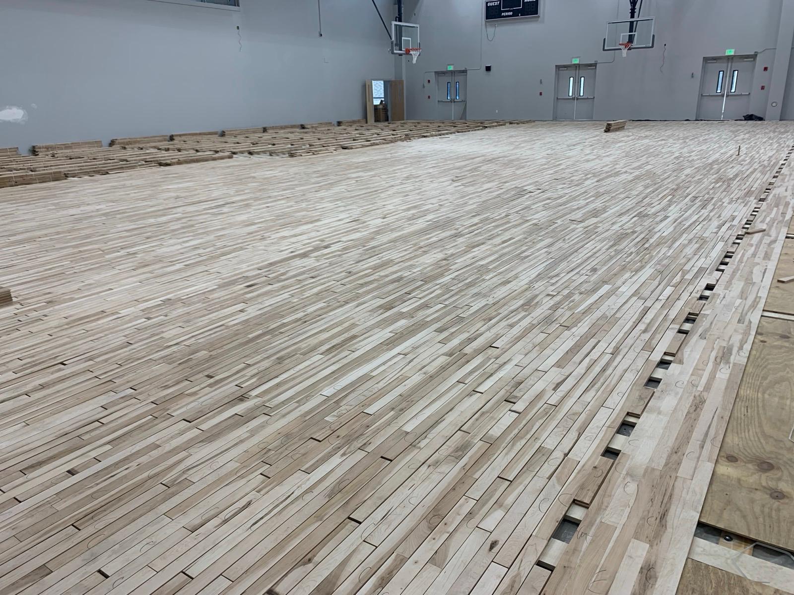 Hardwood gymnasium installation in progress on a commercial GC project