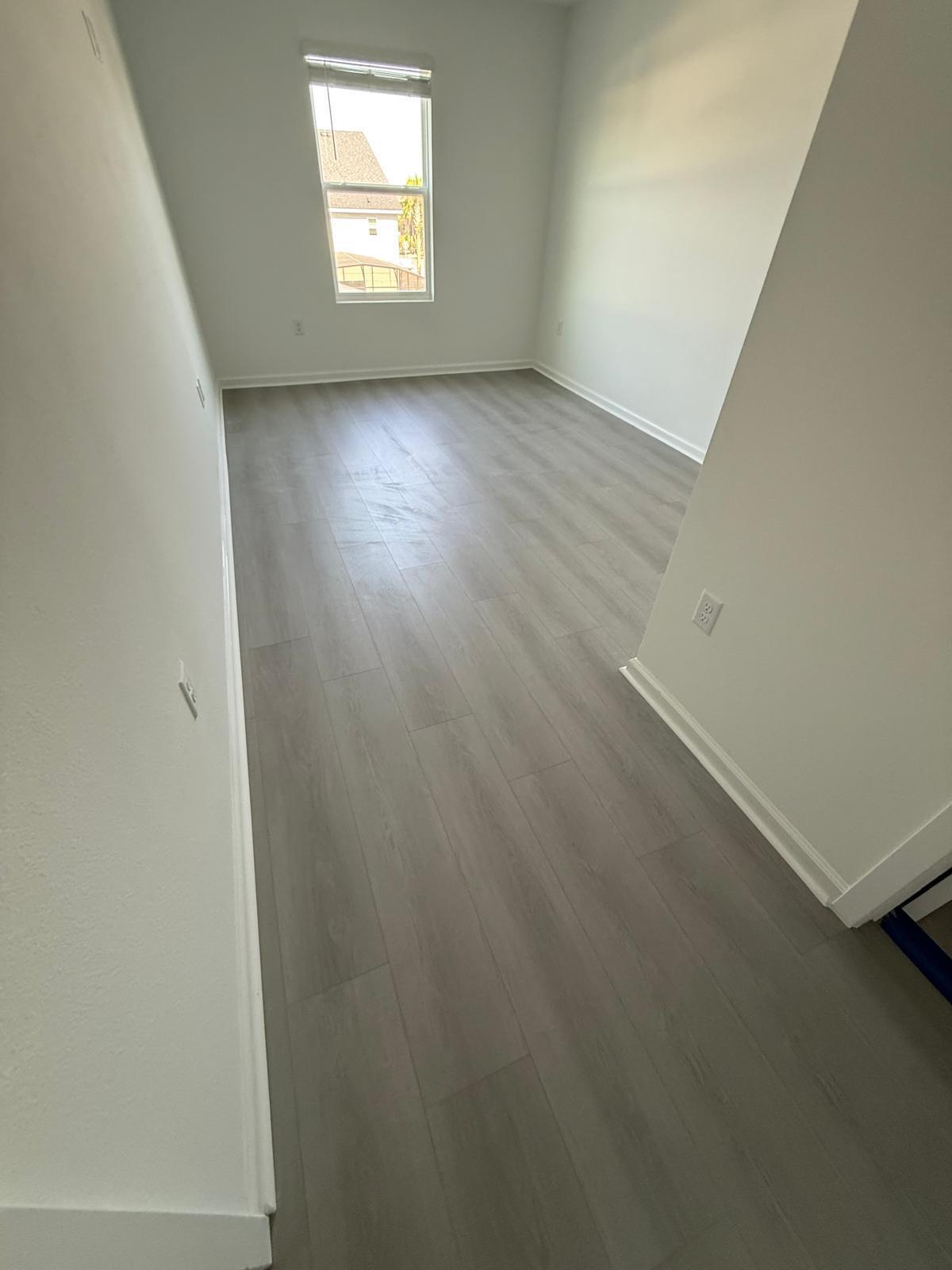Light grey wood-look LVP plank flooring in a small bedroom