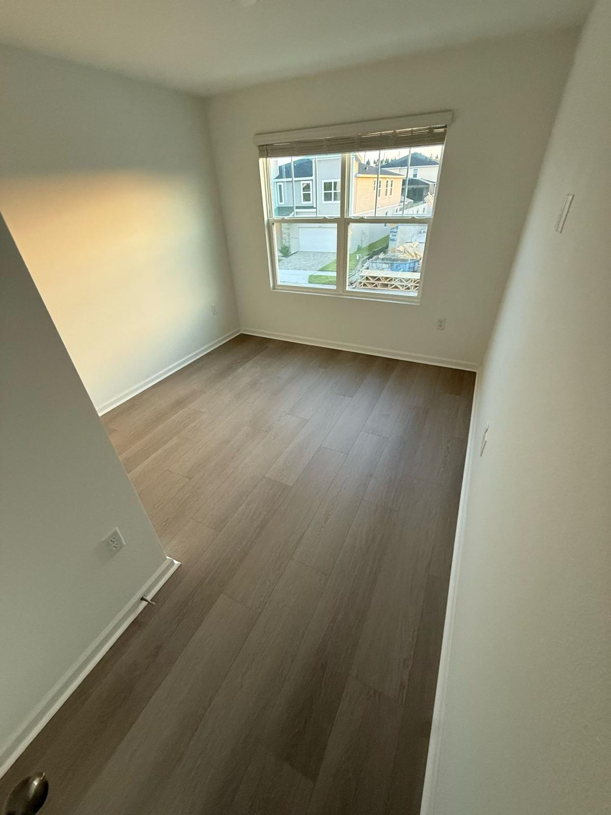 Warm grey LVP plank flooring in a newly built residential bedroom