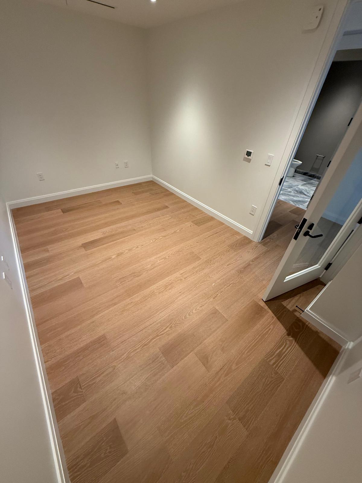 Freshly installed red oak hardwood plank in a small bedroom