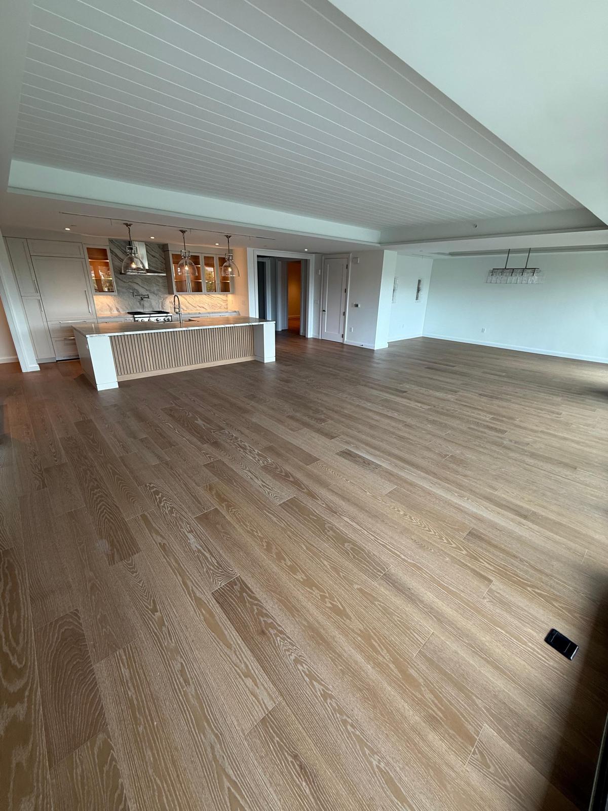 Wide white-oak flooring across a luxury condo great room with open kitchen